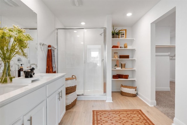 552 Tekoa Dr, Georgetown, TX 78628 - bathroom featuring a shower stall, wood finished floors, double vanity, a spacious closet, and recessed lighting