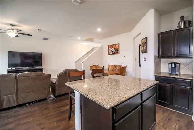 kitchen featuring a kitchen bar, dark wood finished floors, a ceiling fan, open floor plan, and backsplash