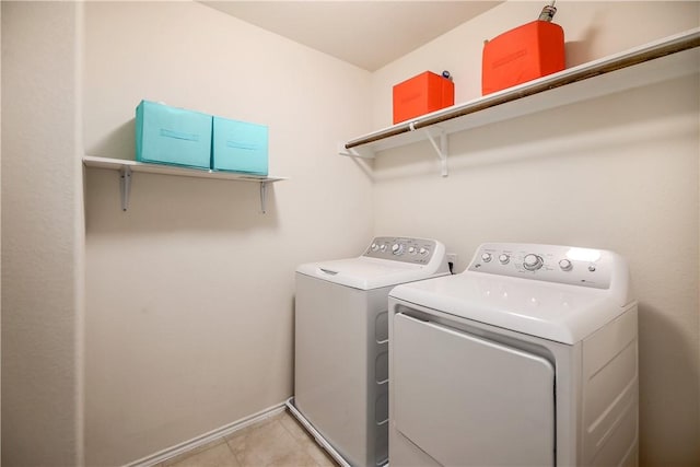 laundry area with independent washer and dryer, light tile patterned floors, and baseboards