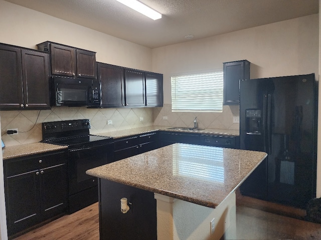 428 Major Lee Ln Unit 10H, Jarrell, TX 76537 - kitchen featuring black appliances, light stone countertops, backsplash, and a center island