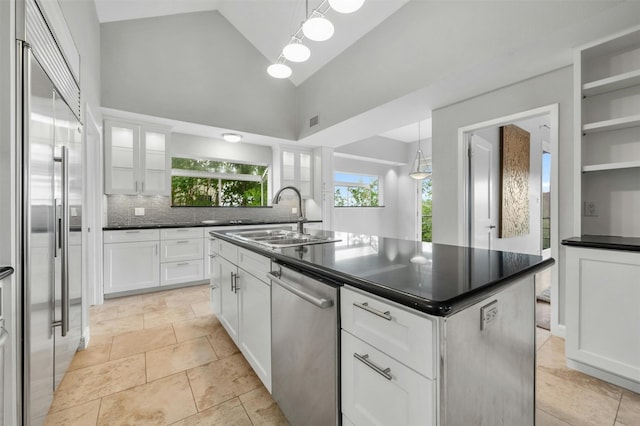 kitchen with stainless steel appliances, a sink, dark countertops, high vaulted ceiling, and white cabinets