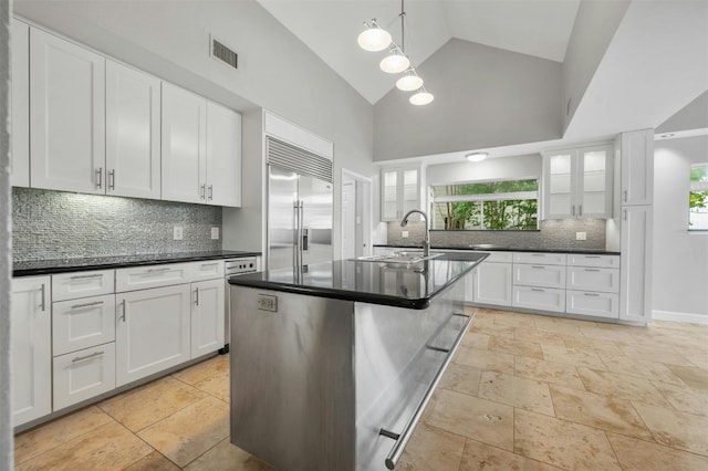 5801 Cannonade Ct, Austin, TX 78746 - kitchen with built in fridge, dark countertops, decorative backsplash, and high vaulted ceiling