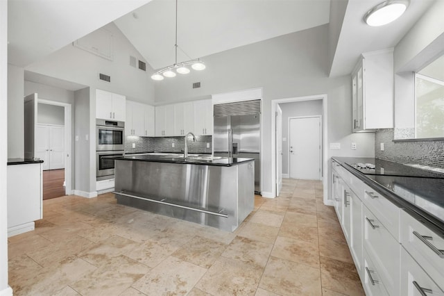 kitchen featuring stainless steel appliances, a sink, dark countertops, decorative backsplash, and high vaulted ceiling