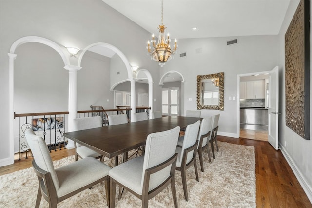 5801 Cannonade Ct, Austin, TX 78746 - dining room featuring ornate columns, a chandelier, wood finished floors, arched walkways, and high vaulted ceiling