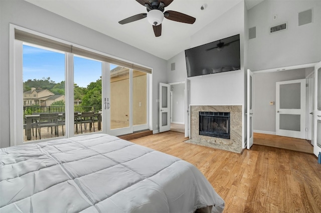 bedroom with high vaulted ceiling, access to outside, a premium fireplace, wood finished floors, and baseboards