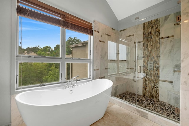 full bathroom with vaulted ceiling, a freestanding tub, plenty of natural light, and a shower stall