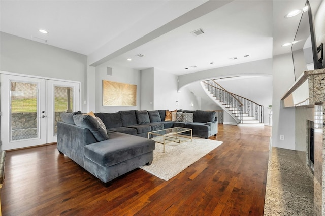 living room featuring stairs, wood finished floors, a fireplace, arched walkways, and recessed lighting