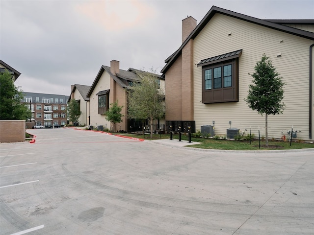 2209 Woodland Ave Unit 501, Austin, TX 78741 - view of side of home featuring mail area, uncovered parking, central AC unit, and a chimney
