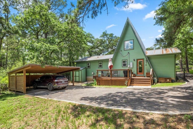 113 S Kanaio Dr, Bastrop, TX 78602 - back of property with asphalt driveway, metal roof, a carport, and a wooden deck
