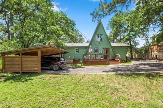 113 S Kanaio Dr, Bastrop, TX 78602 - rear view of house with a yard, driveway, a deck, metal roof, and a carport