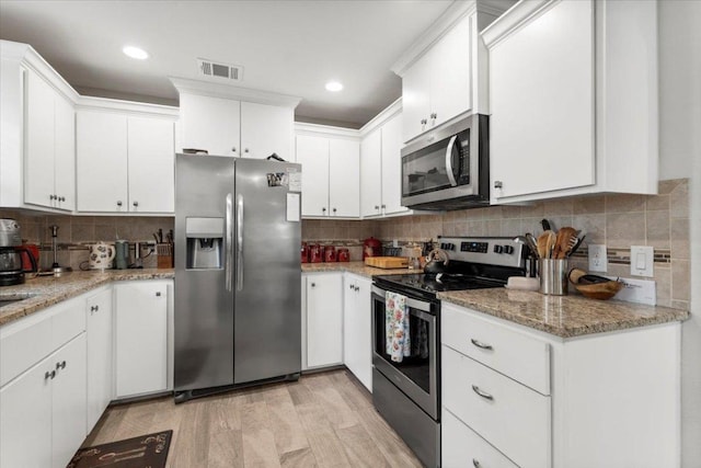113 S Kanaio Dr, Bastrop, TX 78602 - kitchen featuring stainless steel appliances, backsplash, white cabinets, light stone countertops, and recessed lighting