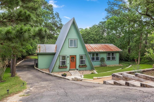 113 S Kanaio Dr, Bastrop, TX 78602 - a-frame style home with metal roof, driveway, and a front lawn
