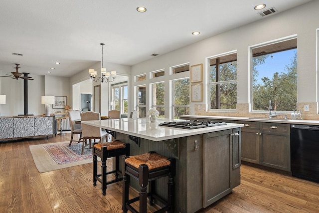 9750-9800 Ledgestone Ter, Austin, TX 78737 - kitchen featuring black dishwasher, a sink, light countertops, gas stovetop, and a kitchen breakfast bar