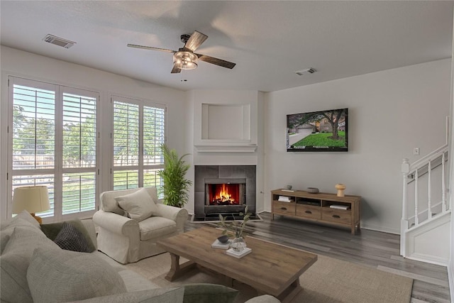 living room featuring a ceiling fan, wood finished floors, a fireplace, baseboards, and stairway