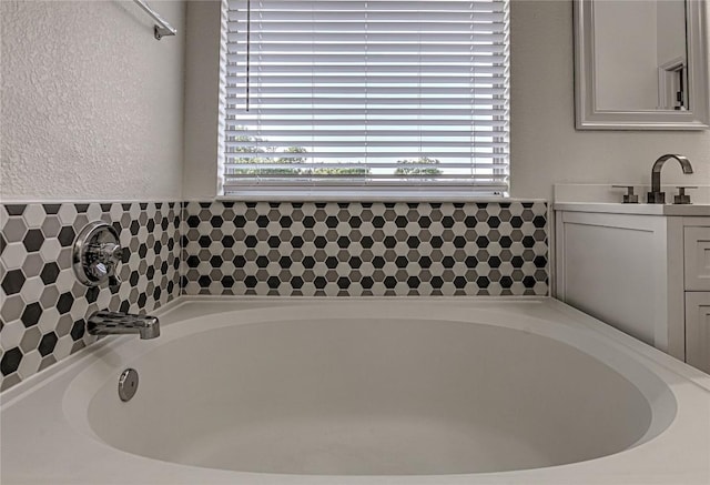 full bath featuring healthy amount of natural light, a bath, and vanity