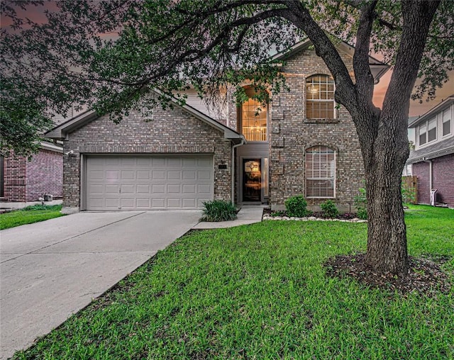 traditional-style house with a garage, concrete driveway, brick siding, and a front lawn