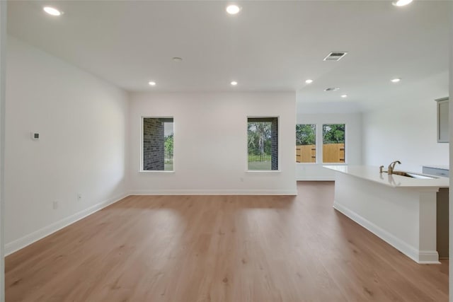 513 Tekoa Dr, Georgetown, TX 78628 - unfurnished living room featuring recessed lighting, light wood finished floors, baseboards, and a sink