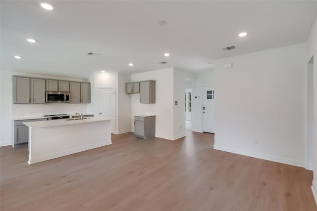 513 Tekoa Dr, Georgetown, TX 78628 - kitchen featuring stainless steel microwave, gray cabinetry, light wood-style floors, recessed lighting, and baseboards