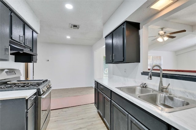 4504 Little Hill Cir, Austin, TX 78725 - kitchen featuring stainless steel gas range oven, ceiling fan, under cabinet range hood, a sink, and light wood-style flooring