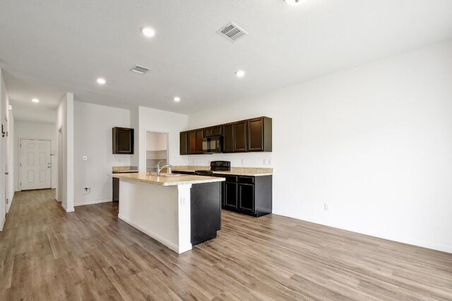 750 Bunton Reserve Blvd, Kyle, TX 78640 - kitchen featuring black appliances, light wood-style floors, a center island with sink, light countertops, and recessed lighting