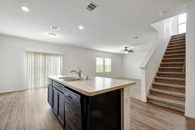 750 Bunton Reserve Blvd, Kyle, TX 78640 - kitchen featuring dishwasher, light countertops, light wood-style floors, ceiling fan, and a center island with sink