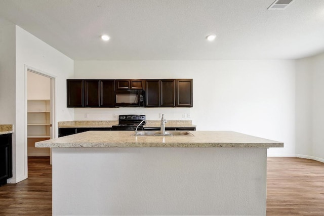 750 Bunton Reserve Blvd, Kyle, TX 78640 - kitchen with black appliances, light countertops, wood finished floors, dark brown cabinets, and a kitchen island with sink