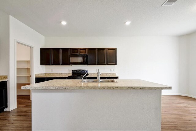 750 Bunton Reserve Blvd, Kyle, TX 78640 - kitchen with black appliances, light countertops, wood finished floors, dark brown cabinets, and a kitchen island with sink