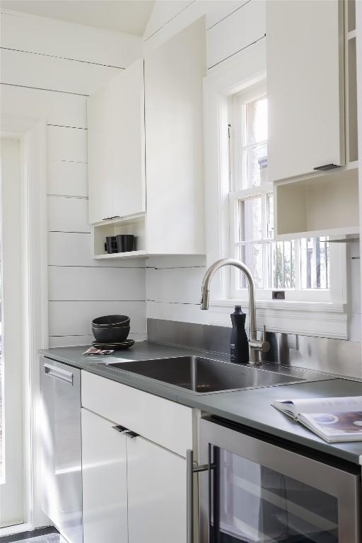 kitchen with white cabinets, a sink, beverage cooler, dishwasher, and modern cabinets