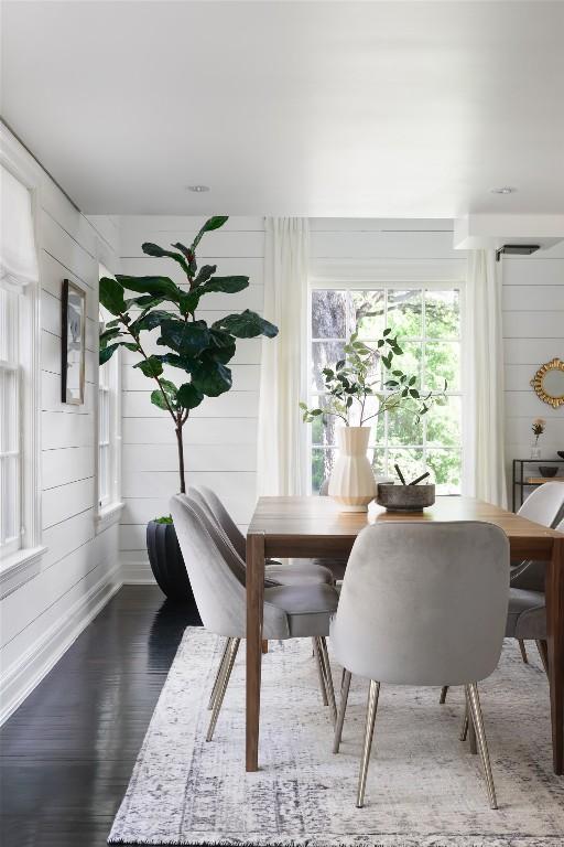 dining room with wood finished floors, baseboards, and wood walls