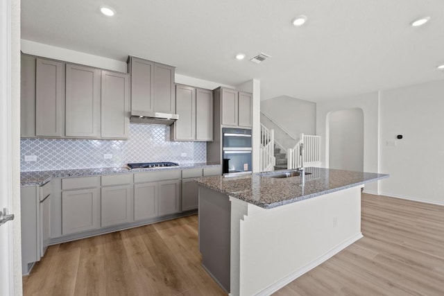3759 Liberi Ln, Round Rock, TX 78665 - kitchen featuring gray cabinetry, a sink, multiple ovens, arched walkways, and recessed lighting