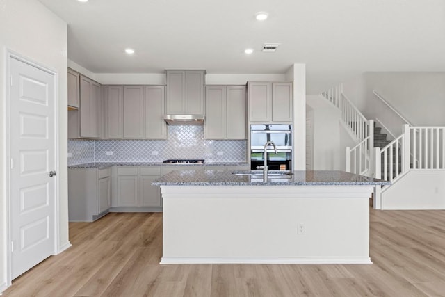 3759 Liberi Ln, Round Rock, TX 78665 - kitchen with gray cabinets, a sink, appliances with stainless steel finishes, light wood finished floors, and backsplash
