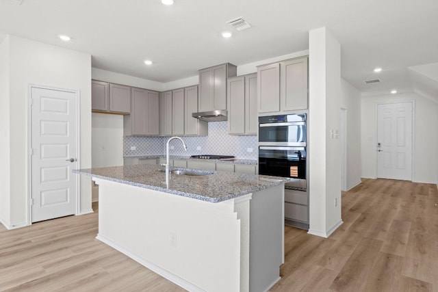 3759 Liberi Ln, Round Rock, TX 78665 - kitchen featuring gray cabinetry, double wall oven, tasteful backsplash, a sink, and light stone counters