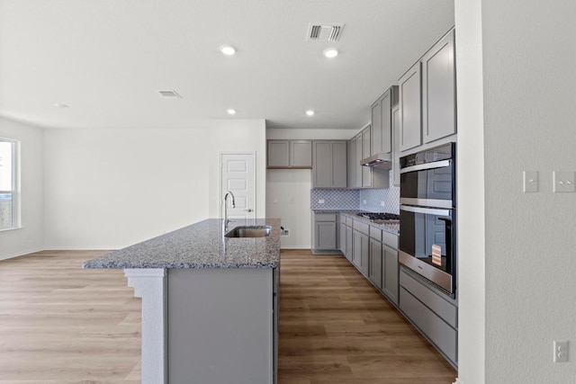 3759 Liberi Ln, Round Rock, TX 78665 - kitchen featuring gray cabinets, a sink, stainless steel appliances, light stone counters, and backsplash