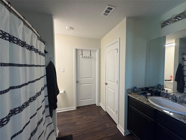 721 Yearwood Ln Unit 45E, Jarrell, TX 76537 - bathroom featuring wood finished floors, vanity, baseboards, a textured ceiling, and curtained shower