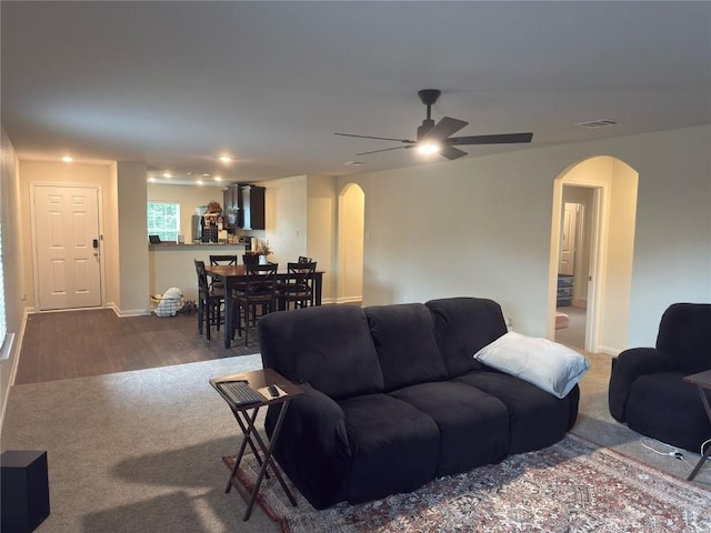 721 Yearwood Ln Unit 45E, Jarrell, TX 76537 - carpeted living area with arched walkways, ceiling fan, baseboards, and wood finished floors