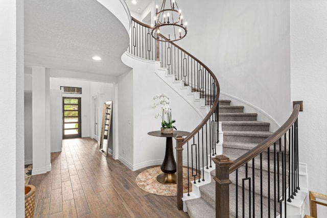 foyer with stairway, wood finished floors, baseboards, recessed lighting, and a chandelier