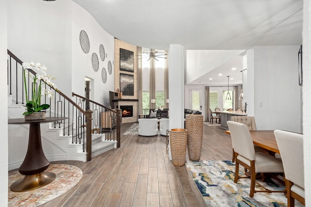 entrance foyer with stairs, wood finished floors, a large fireplace, and a ceiling fan