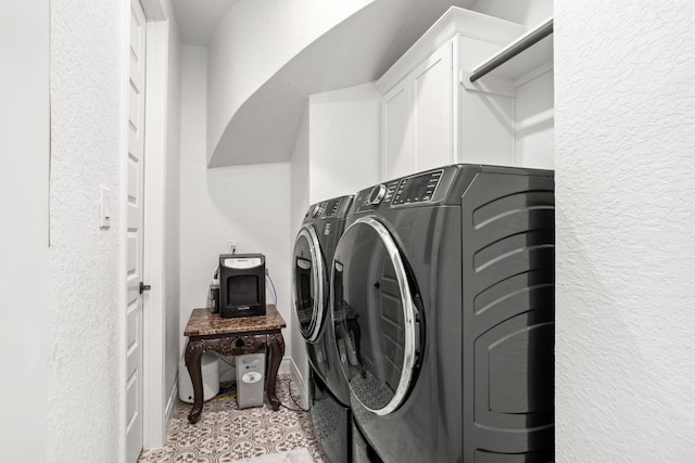 laundry room featuring washer and clothes dryer, cabinet space, and a textured wall