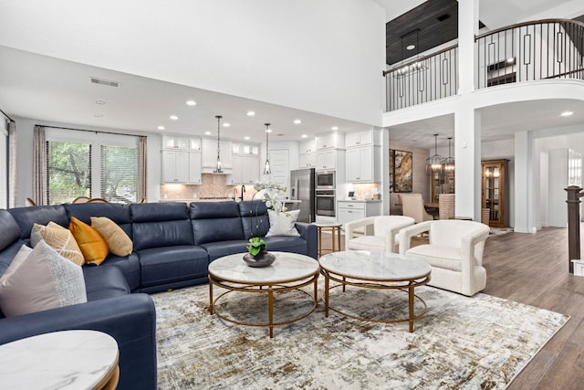 living area featuring recessed lighting, wood finished floors, and a towering ceiling