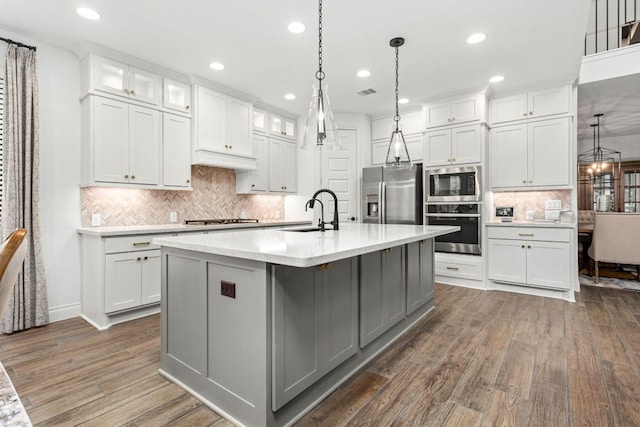 kitchen featuring stainless steel appliances, a sink, recessed lighting, dark wood-style floors, and decorative backsplash