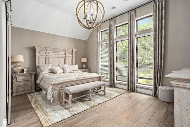 bedroom featuring a chandelier, vaulted ceiling, wood finished floors, and multiple windows