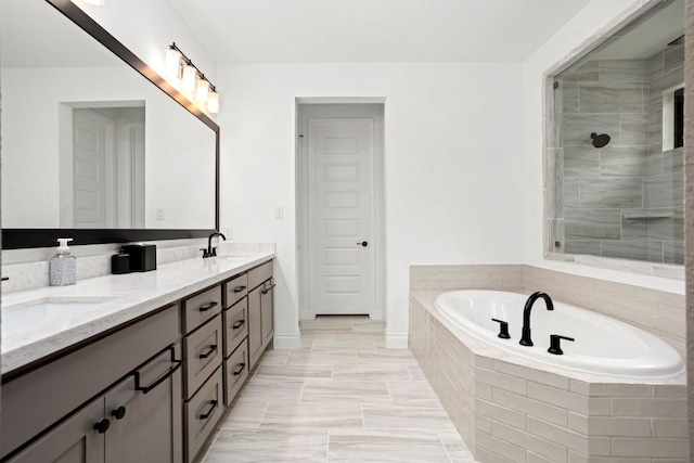 bathroom with a garden tub, tiled shower, double vanity, and baseboards