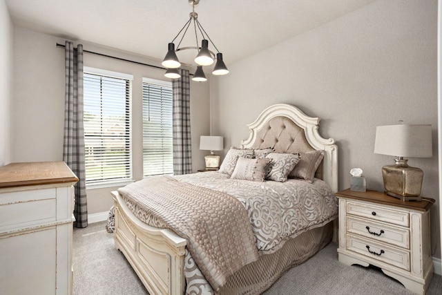 bedroom with light carpet, a chandelier, and baseboards