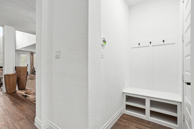 mudroom featuring dark wood-style floors, a textured wall, and baseboards