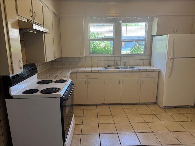 1711 Singleton Ave, Austin, TX 78702 - kitchen featuring range with electric cooktop, freestanding refrigerator, under cabinet range hood, a sink, and tile countertops