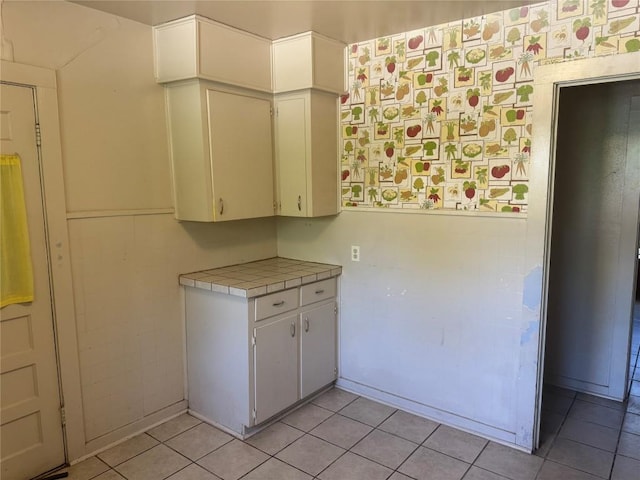 1711 Singleton Ave, Austin, TX 78702 - kitchen featuring wallpapered walls, tile countertops, light tile patterned floors, and white cabinets