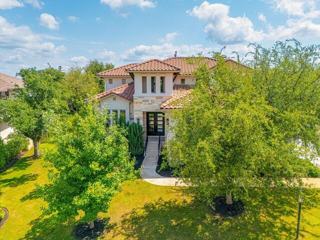 406 Woodside Ter, Austin, TX 78738 - mediterranean / spanish house featuring stone siding, french doors, stucco siding, a tiled roof, and a front lawn
