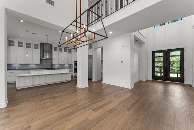 kitchen with a high ceiling, open floor plan, a sink, wood finished floors, and light countertops