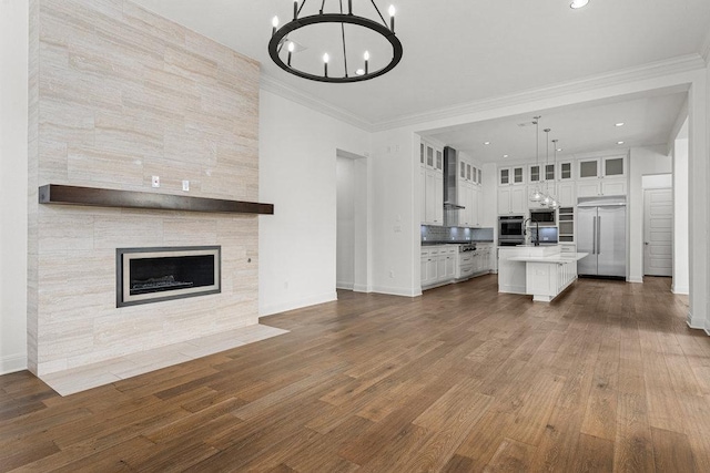 unfurnished living room featuring a chandelier, dark wood-type flooring, baseboards, recessed lighting, and ornamental molding
