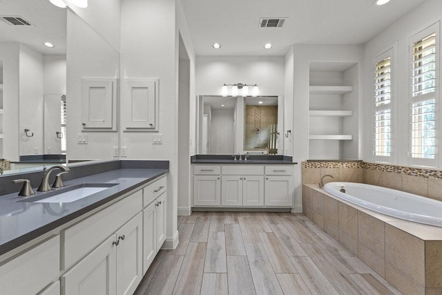 406 Woodside Ter, Austin, TX 78738 - full bathroom with two vanities, a bath, plenty of natural light, wood finished floors, and recessed lighting